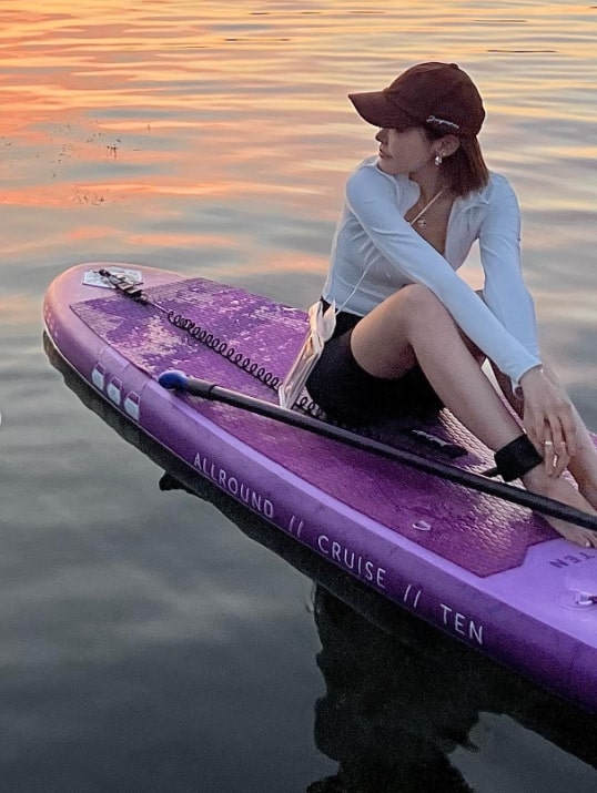 purple paddle board with pretty girl sitting on it