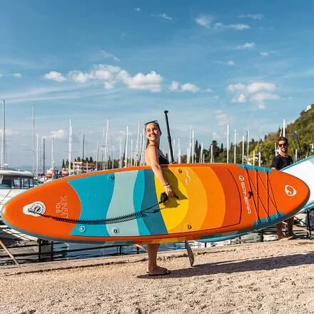 pretty girl smiling while holding the Spinera sunet 10'6" paddle board