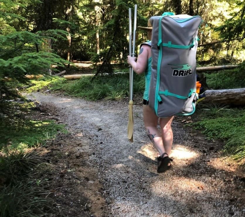 drift paddle board bag on a womans back while walking in the forest.