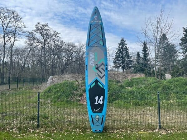 racing paddle board standing up on a fence on a partly cloudy day