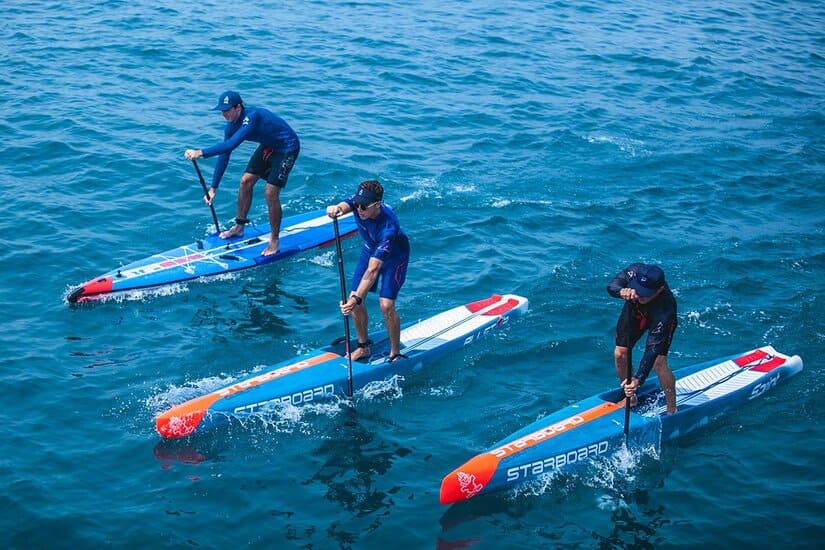 3 men racing on paddle boards